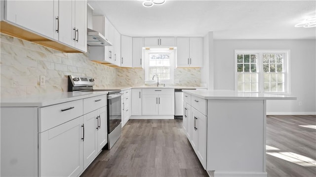 kitchen featuring electric stove, light hardwood / wood-style floors, a kitchen island, backsplash, and white cabinetry