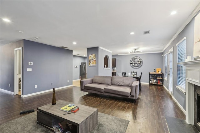 living room featuring a high end fireplace, dark wood-type flooring, and ornamental molding