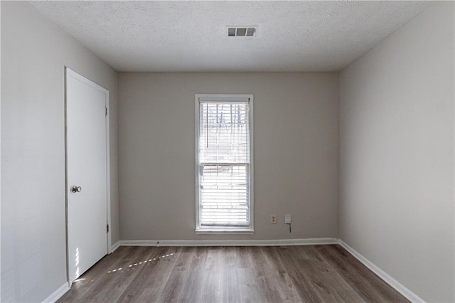 spare room with dark wood-type flooring and a textured ceiling