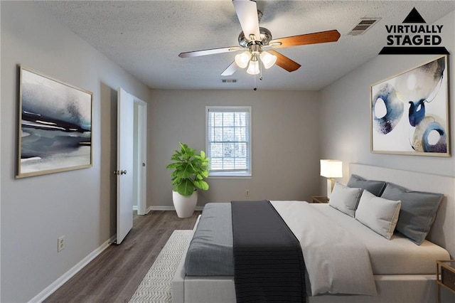 bedroom with ceiling fan, dark hardwood / wood-style floors, and a textured ceiling