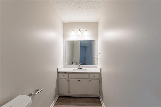 bathroom featuring hardwood / wood-style flooring, vanity, toilet, and a textured ceiling