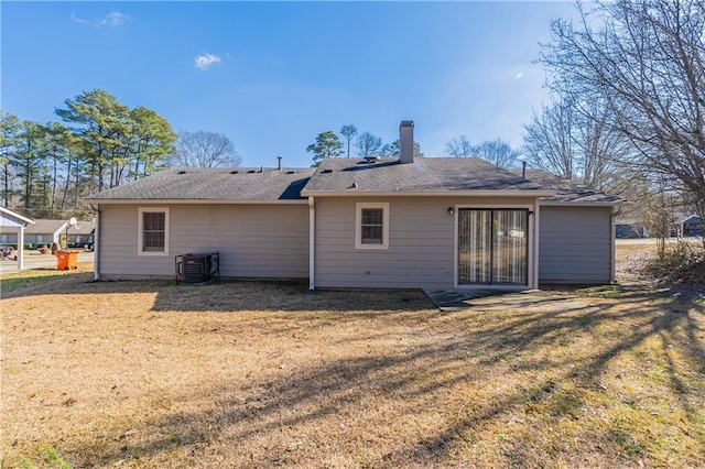 rear view of property with a lawn and central air condition unit