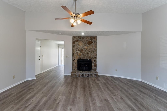 unfurnished living room with ceiling fan, a fireplace, dark hardwood / wood-style flooring, and a textured ceiling