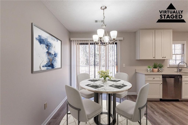 dining space with sink, a notable chandelier, and light wood-type flooring