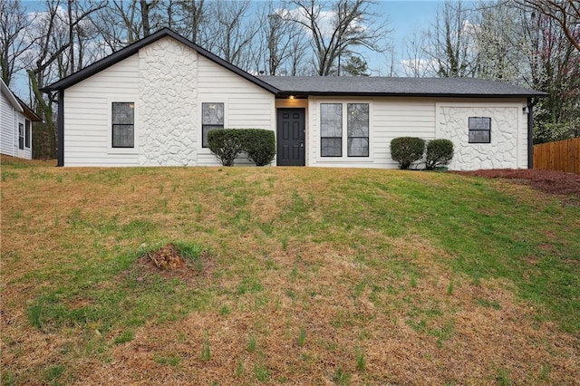 ranch-style house featuring a front lawn and fence