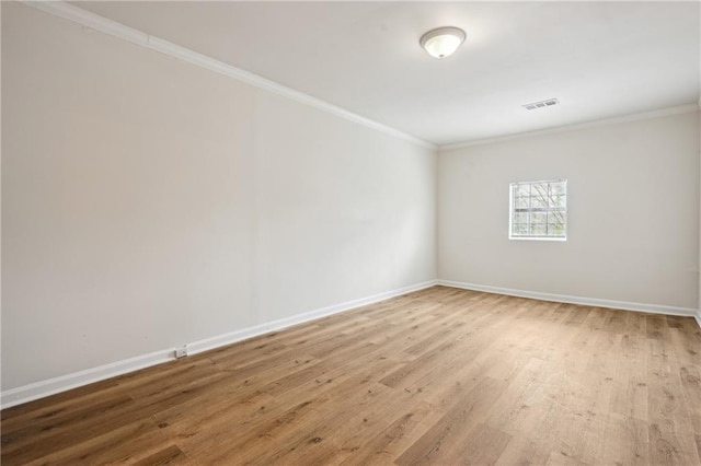 spare room featuring visible vents, wood finished floors, baseboards, and ornamental molding