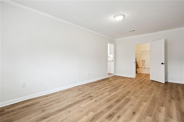 spare room with light wood-type flooring, visible vents, baseboards, and crown molding