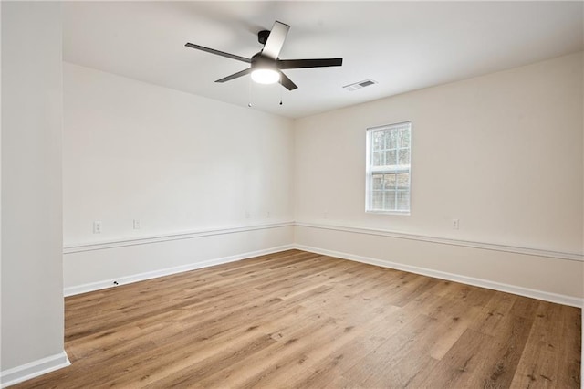 unfurnished room with visible vents, a ceiling fan, baseboards, and wood finished floors