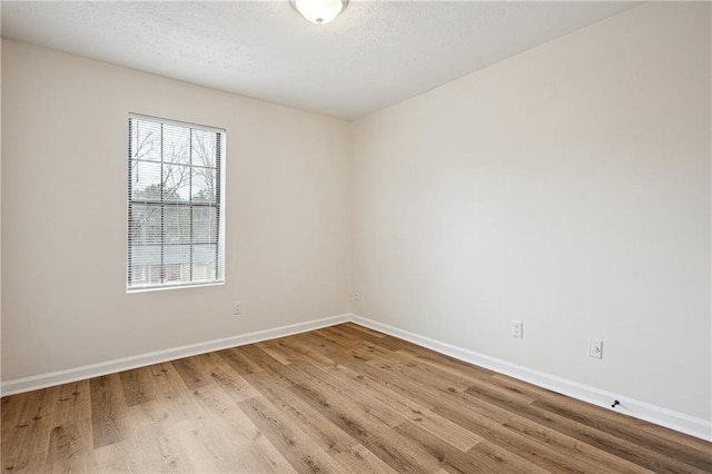 empty room featuring wood finished floors, baseboards, and a textured ceiling