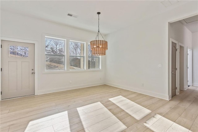 unfurnished dining area featuring light wood-type flooring, visible vents, baseboards, and an inviting chandelier