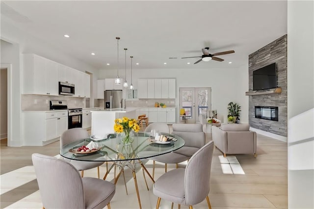 dining room with recessed lighting, a fireplace, a ceiling fan, and light wood finished floors