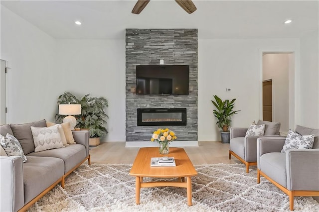 living area with wood finished floors, recessed lighting, a ceiling fan, and a large fireplace