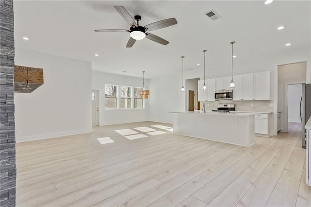 unfurnished living room featuring recessed lighting, visible vents, ceiling fan with notable chandelier, and light wood-style flooring