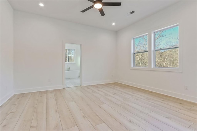 spare room with light wood finished floors, plenty of natural light, visible vents, and a ceiling fan