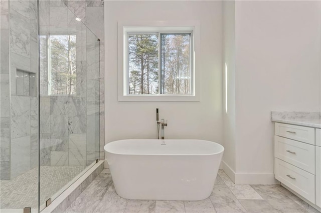 bathroom featuring marble finish floor, a stall shower, baseboards, a freestanding bath, and vanity