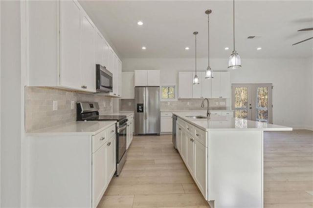 kitchen with light wood finished floors, a sink, tasteful backsplash, stainless steel appliances, and light countertops