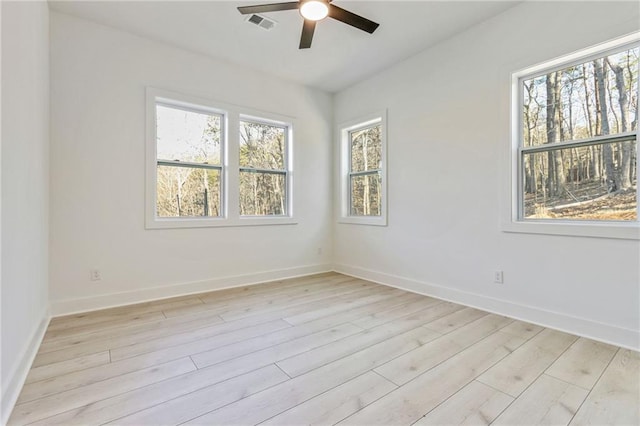 empty room featuring visible vents, light wood-style flooring, baseboards, and a ceiling fan