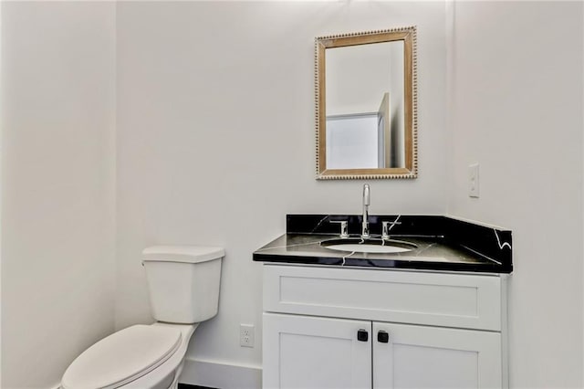 half bathroom featuring vanity, toilet, and baseboards