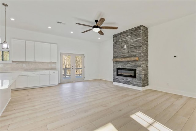 unfurnished living room with visible vents, recessed lighting, a stone fireplace, light wood finished floors, and ceiling fan