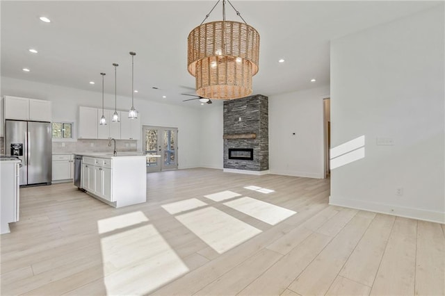 kitchen featuring a sink, tasteful backsplash, open floor plan, stainless steel appliances, and light countertops