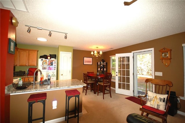 70 Darbys Crossing Ct, Hiram, GA 30141 - kitchen with freestanding refrigerator, a peninsula, a chandelier, light carpet, and light stone countertops