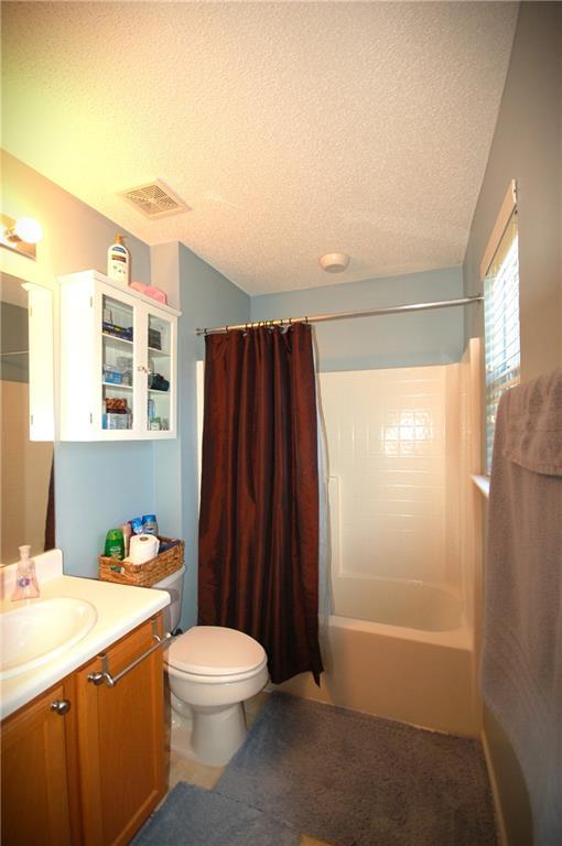 70 Darbys Crossing Ct, Hiram, GA 30141 - bathroom with vanity, a textured ceiling, shower / tub combo, and toilet