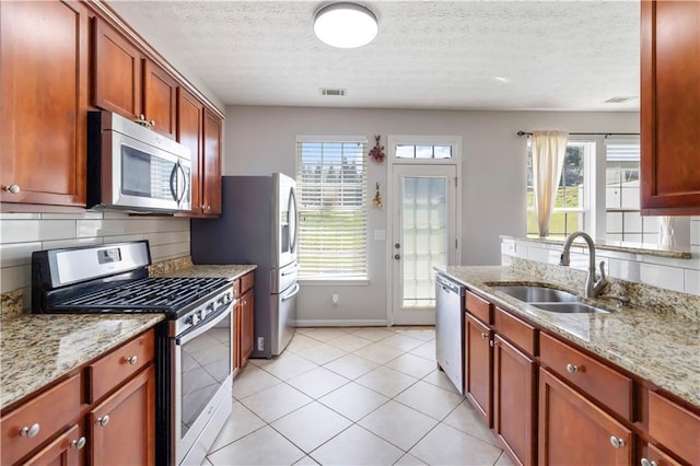 5351 Paramount View Way, Sugar Hill, GA 30518 - kitchen featuring appliances with stainless steel finishes, light stone counters, a textured ceiling, light tile patterned floors, and backsplash
