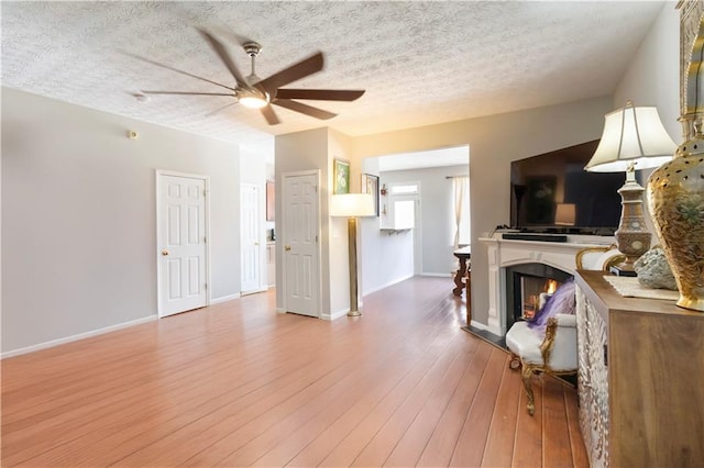 5351 Paramount View Way, Sugar Hill, GA 30518 - living area with a ceiling fan, a textured ceiling, wood finished floors, and a warm lit fireplace