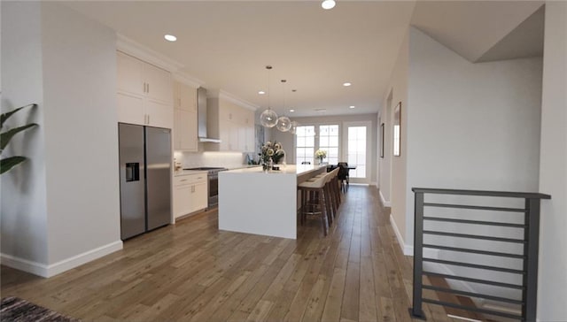 kitchen with appliances with stainless steel finishes, decorative light fixtures, white cabinets, dark wood-type flooring, and a kitchen island with sink