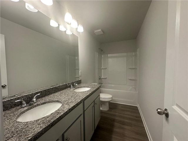 full bath with a sink, baseboards, double vanity, and wood finished floors