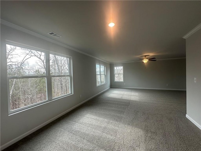 carpeted empty room featuring baseboards, ornamental molding, ceiling fan, and visible vents