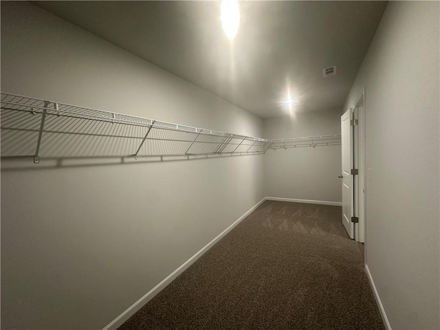 spacious closet with dark carpet and visible vents