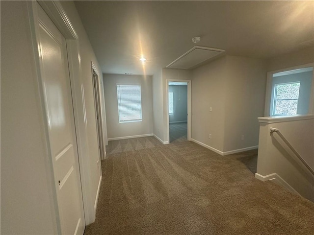 carpeted spare room with baseboards and attic access