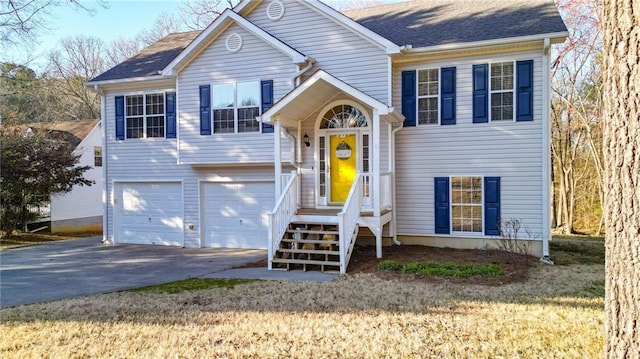 raised ranch featuring driveway, a shingled roof, and a garage