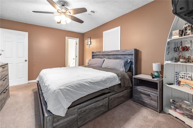 bedroom featuring visible vents, light carpet, a textured ceiling, and a ceiling fan