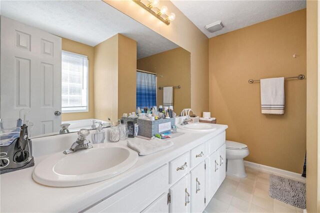 full bathroom featuring visible vents, toilet, a sink, a textured ceiling, and double vanity