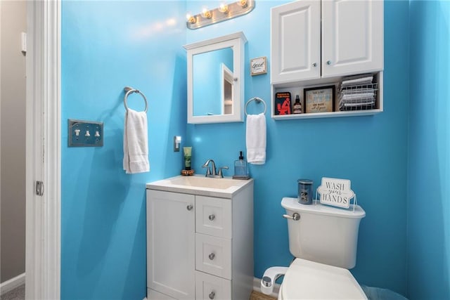 bathroom featuring baseboards, toilet, and vanity