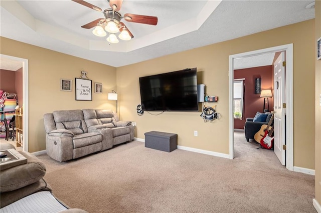 living room with baseboards, a raised ceiling, and carpet