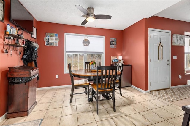 dining area with baseboards, a textured ceiling, light tile patterned flooring, and a ceiling fan