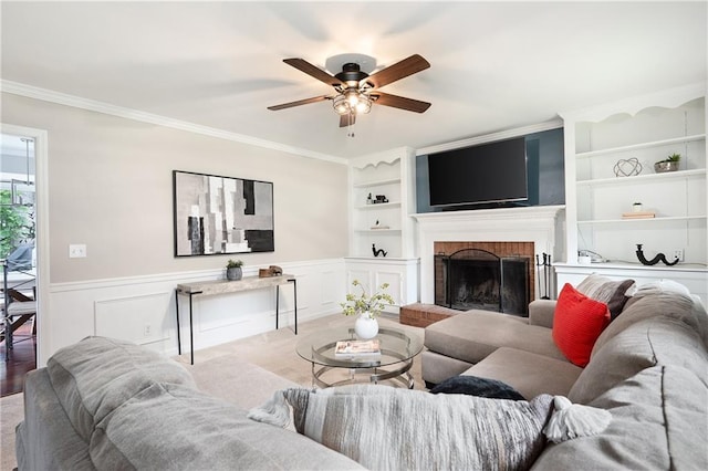4497 Windsor Oaks Dr, Marietta, GA 30066 - living room featuring a brick fireplace, ceiling fan, crown molding, built in shelves, and a wainscoted wall