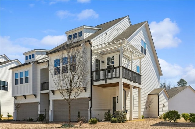 view of front of home featuring a balcony, an attached garage, a pergola, and driveway