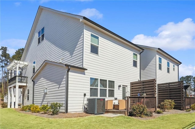 back of property featuring cooling unit, a lawn, and a wooden deck