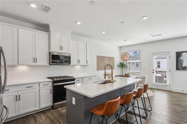 kitchen featuring stainless steel microwave, range with electric cooktop, visible vents, decorative backsplash, and a sink