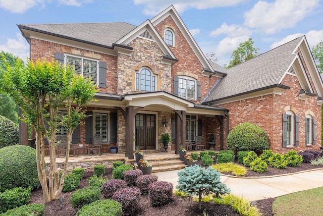view of front of house with a porch, brick siding, and a shingled roof