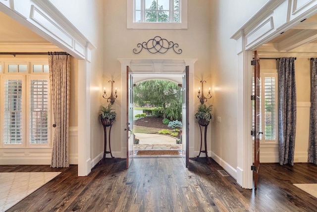 foyer entrance with baseboards, wood finished floors, and a towering ceiling