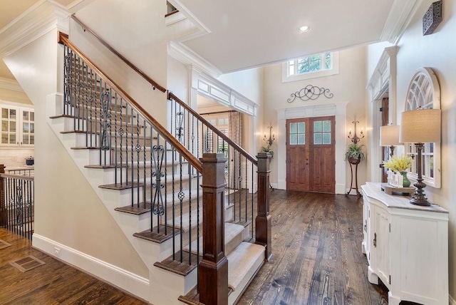 foyer entrance with stairway, baseboards, dark wood-style flooring, and visible vents