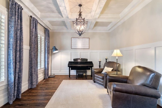 living area with a decorative wall, beam ceiling, wood finished floors, a chandelier, and coffered ceiling