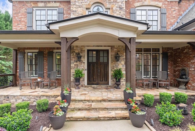 doorway to property with covered porch and stone siding