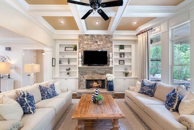 living area with ceiling fan, a fireplace, beamed ceiling, ornamental molding, and coffered ceiling