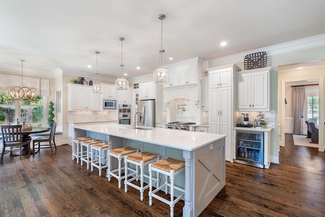 kitchen with decorative backsplash, wine cooler, light countertops, a chandelier, and stainless steel appliances
